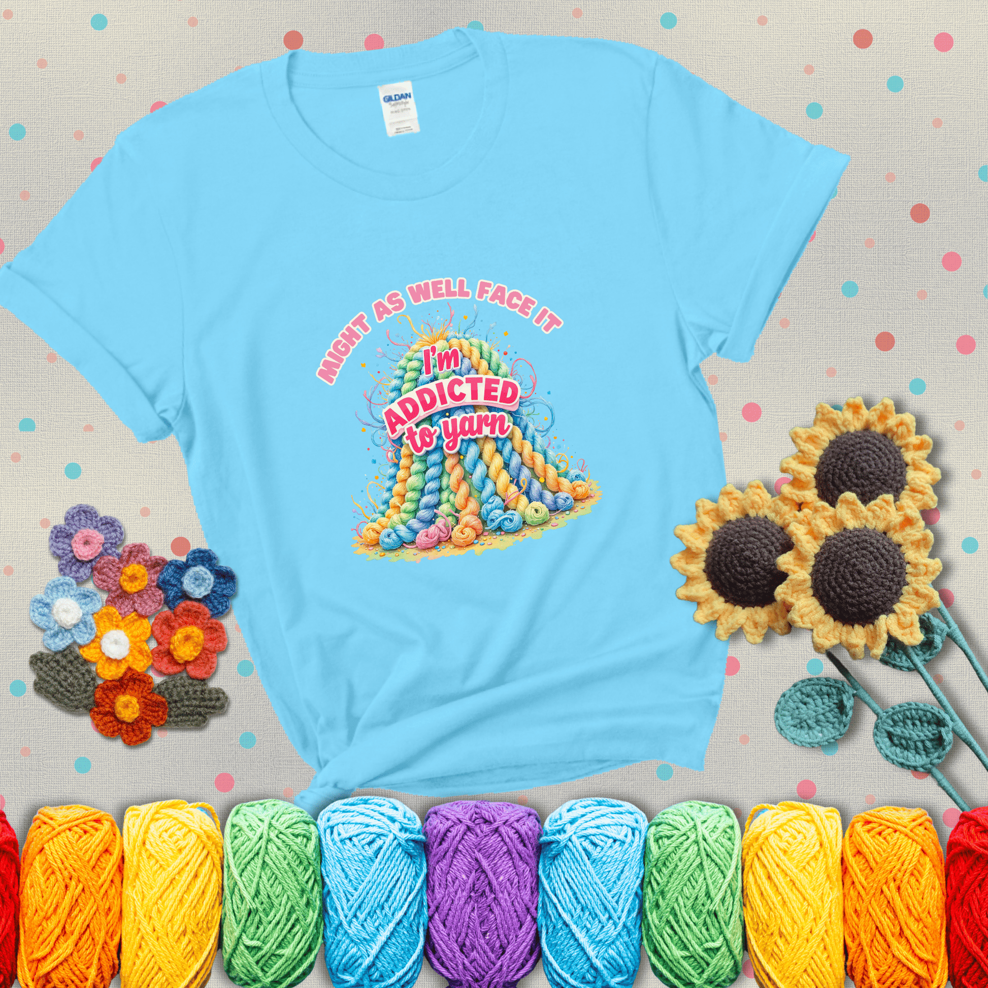 Colorful mountain of pastel yarn hanks with the phrase “Might as well face it, I’m addicted to yarn” in playful pink and red lettering showing a light blue tee with grey sunflower background