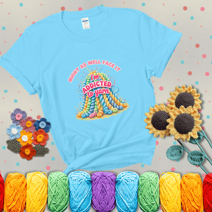 Colorful mountain of pastel yarn hanks with the phrase “Might as well face it, I’m addicted to yarn” in playful pink and red lettering showing a light blue tee with grey sunflower background