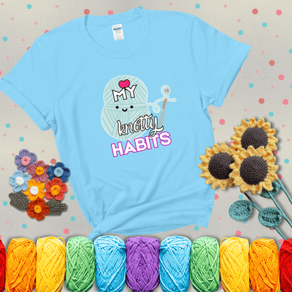 Smiling yarn ball and hook with text “Love My Knotty Habits” - cute crochet shirt with playful design for makers, showing a light blue tee with grey sunflower background