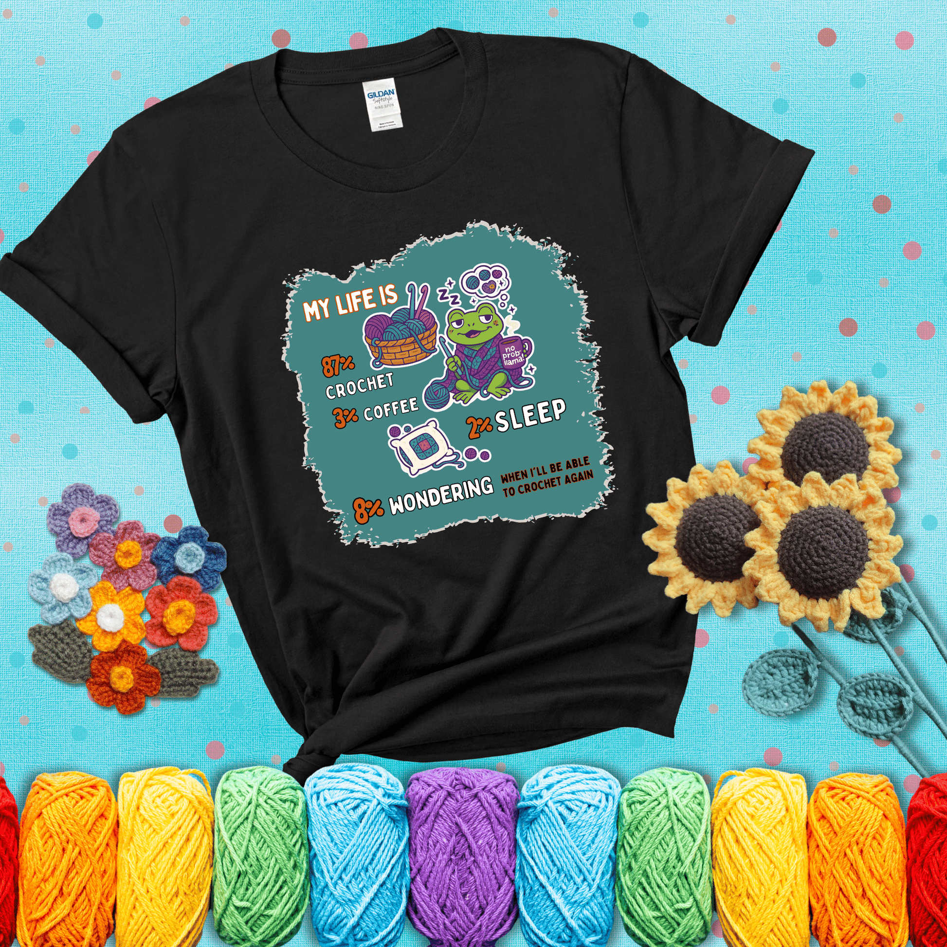 A relaxed frog crocheting while sipping coffee, surrounded by yarn and dreaming of more yarn. Includes whimsical text dividing life into percentages: 87% crochet, 3% coffee, 2% sleep, 8% wondering when to crochet again showing a black tee with a teal sunflower background