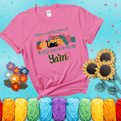 Illustration of a black cat playing with yarn next to a basket full of colorful skeins, with the phrase "Not sure what the question is, but the answer is always yarn" showing a pink tee with a teal sunflower background