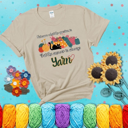 Illustration of a black cat playing with yarn next to a basket full of colorful skeins, with the phrase "Not sure what the question is, but the answer is always yarn" showing a beige tee with a teal sunflower background