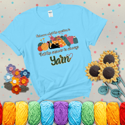 Illustration of a black cat playing with yarn next to a basket full of colorful skeins, with the phrase "Not sure what the question is, but the answer is always yarn" showing a blue-green tee with a teal sunflower background