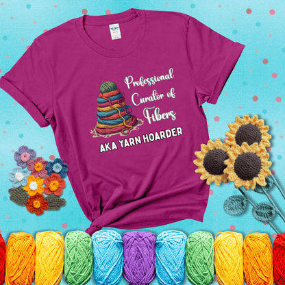 Pyramid of rainbow yarn topped with green ball; text reads “Professional Curator of Fibers AKA Yarn Hoarder,” a playful shirt for serious stashers showing a magenta tee with a teal sunflower background