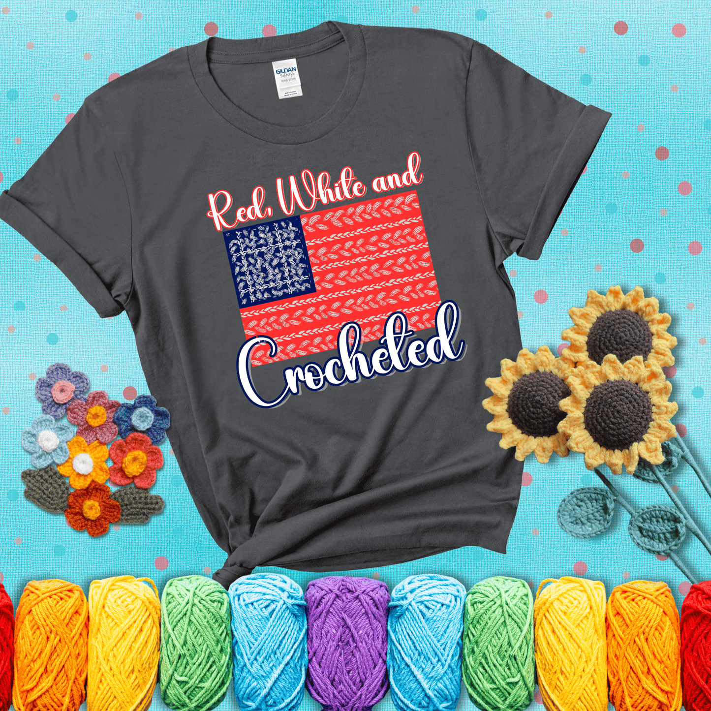Patriotic crochet-themed American flag design with red and white yarn stitches forming the stripes and blue and white stitches as stars, showing a dark grey tee with a teal sunflower background