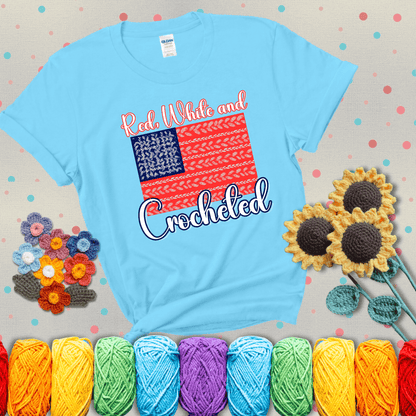 Patriotic crochet-themed American flag design with red and white yarn stitches forming the stripes and blue and white stitches as stars, showing a light blue tee with grey sunflower background