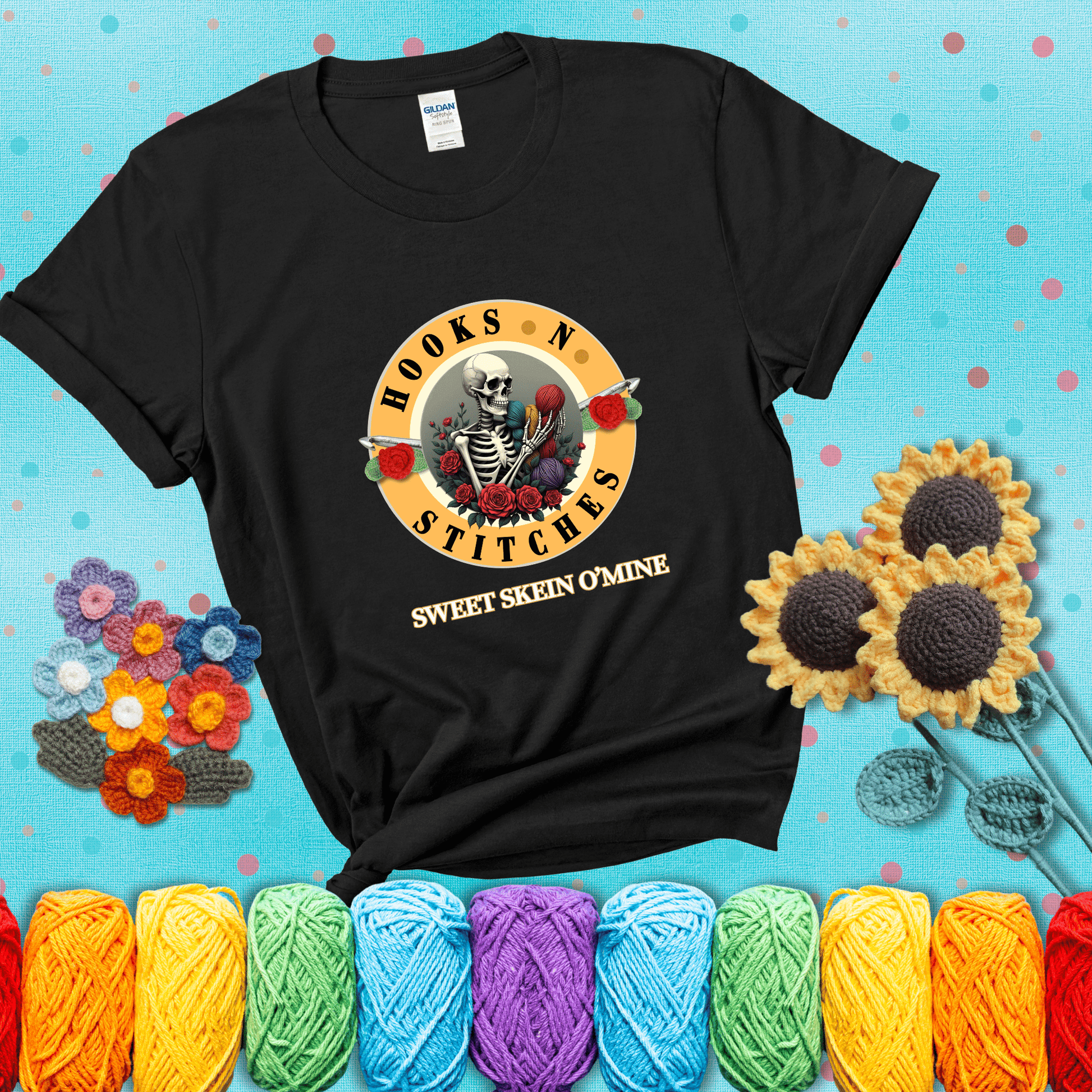 A skeleton holding colorful yarn, surrounded by roses, framed in a circular logo-style design that says “Hooks 'N Stitches” and “Sweet Skein O’Mine,” with crochet hooks piercing through showing a black tee with a teal sunflower background