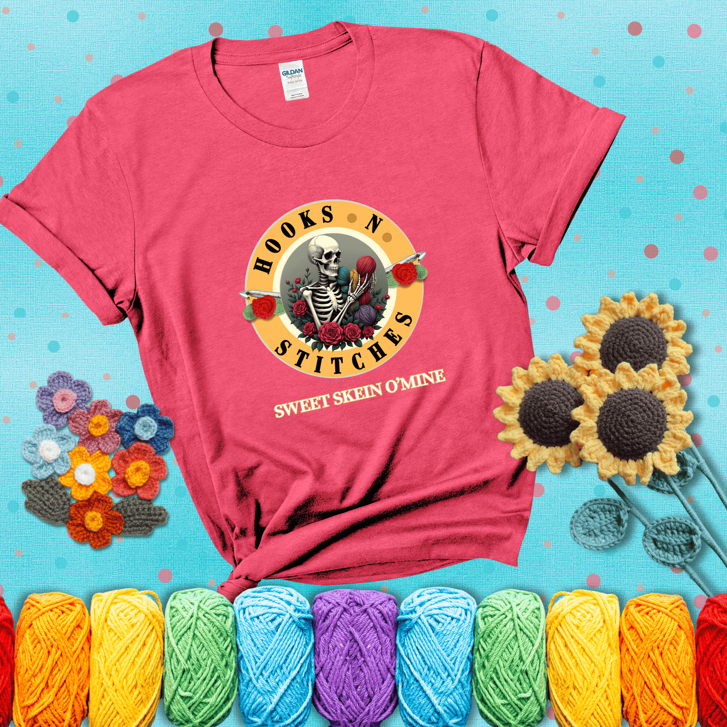 A skeleton holding colorful yarn, surrounded by roses, framed in a circular logo-style design that says “Hooks 'N Stitches” and “Sweet Skein O’Mine,” with crochet hooks piercing through showing a light red tee with a teal sunflower background