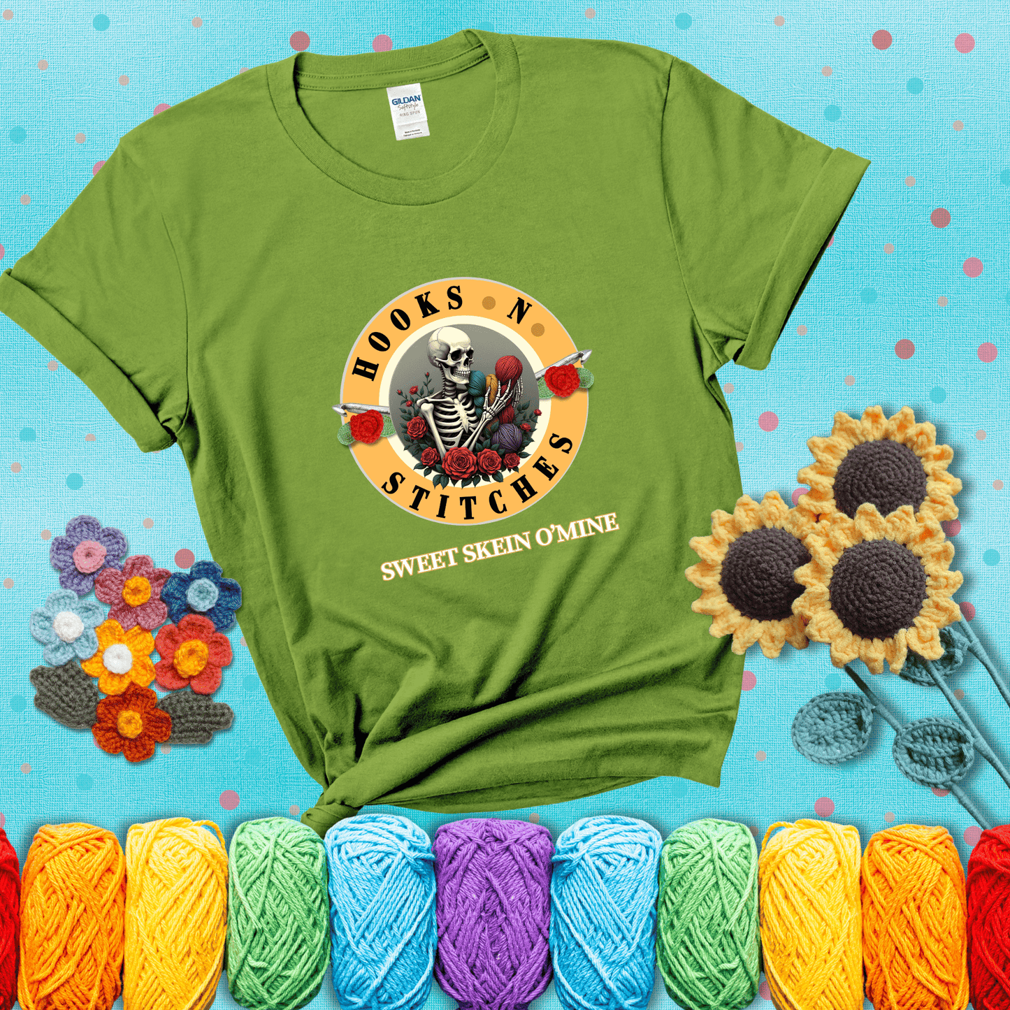 A skeleton holding colorful yarn, surrounded by roses, framed in a circular logo-style design that says “Hooks 'N Stitches” and “Sweet Skein O’Mine,” with crochet hooks piercing through showing a bright green tee with a teal sunflower background
