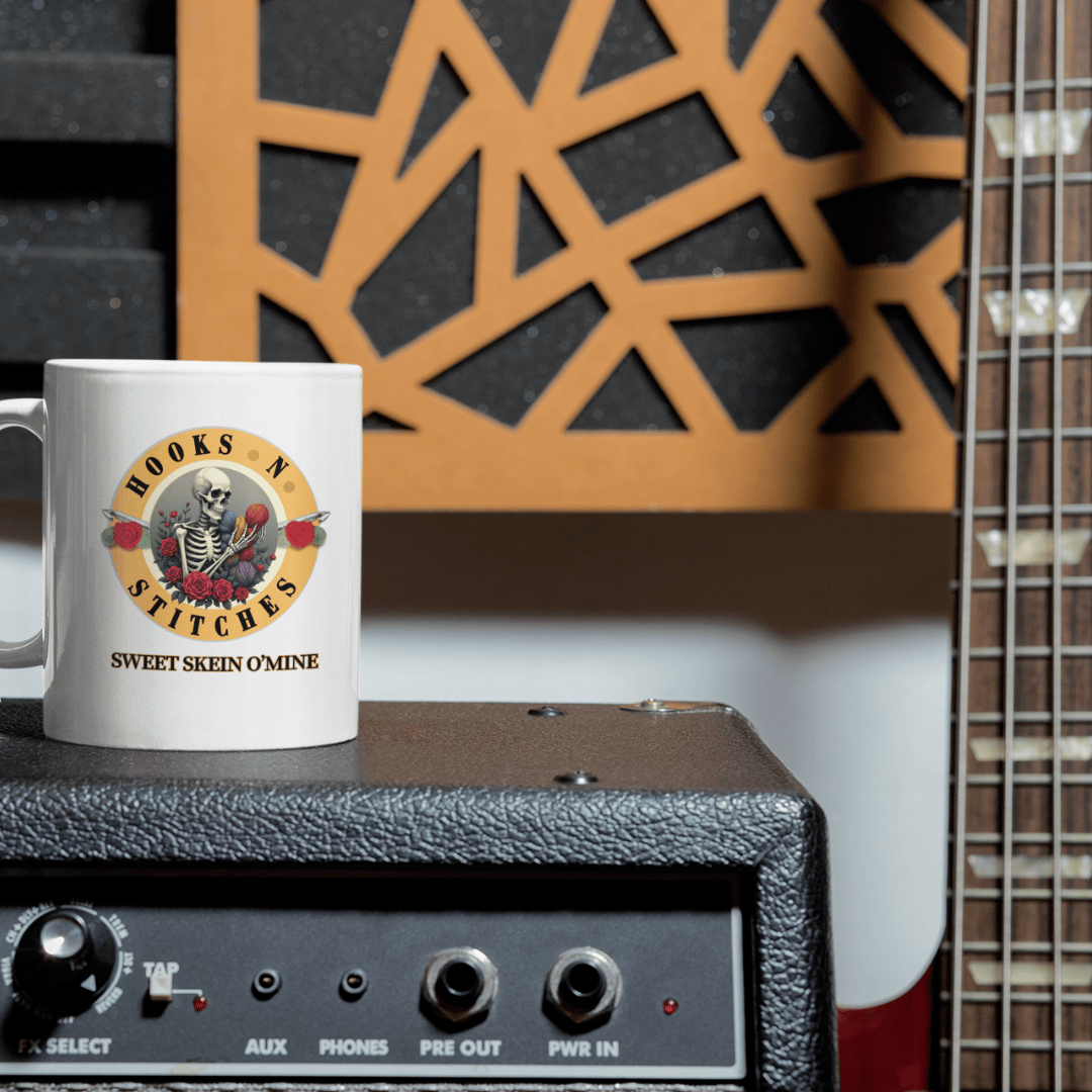 Sweet Skein O’ Mine crochet parody mug on a guitar amplifier, with a bass guitar in the background.