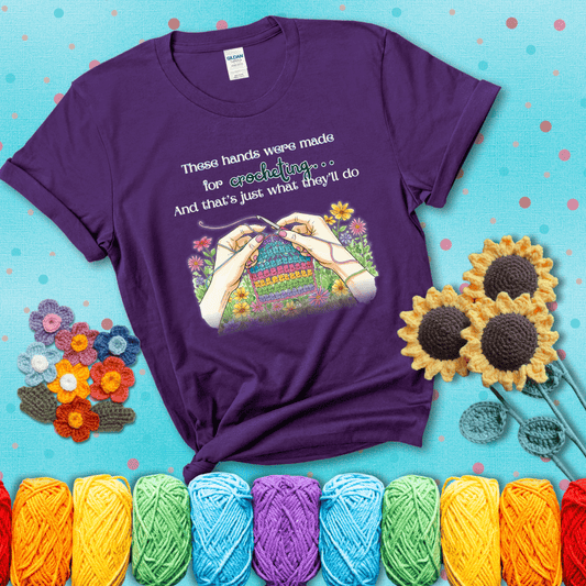 Illustration of two hands crocheting a rainbow swatch, surrounded by vibrant flowers with the phrase “These hands were made for crocheting… and that’s just what they’ll do,” showing a purple tee with a teal sunflower background