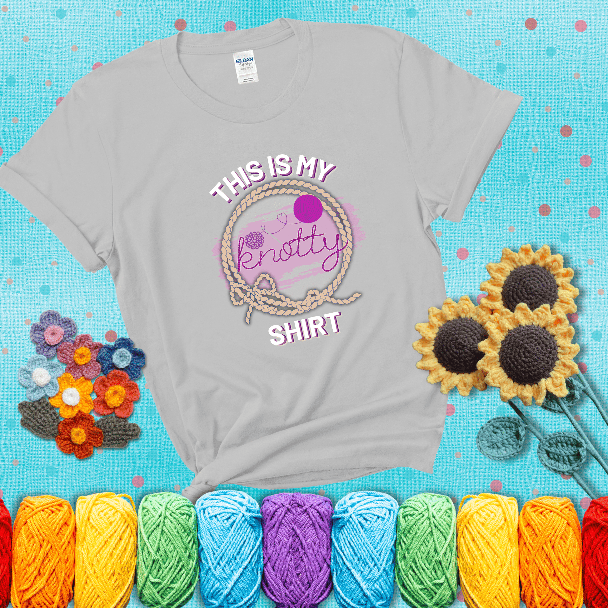 A playful design with the phrase "This is my knotty shirt" inside a rope circle, featuring a yarn ball and a crochet hook forming the word "knotty" showing a light grey tee with a teal sunflower background