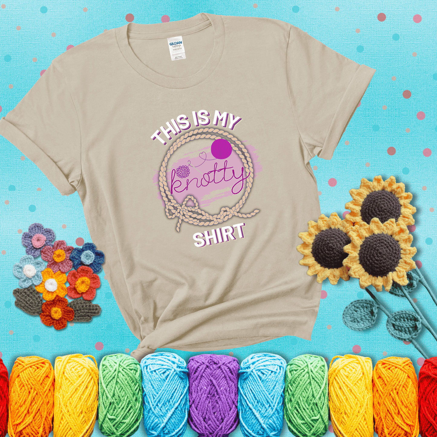 A playful design with the phrase "This is my knotty shirt" inside a rope circle, featuring a yarn ball and a crochet hook forming the word "knotty" showing a beige tee with a teal sunflower background