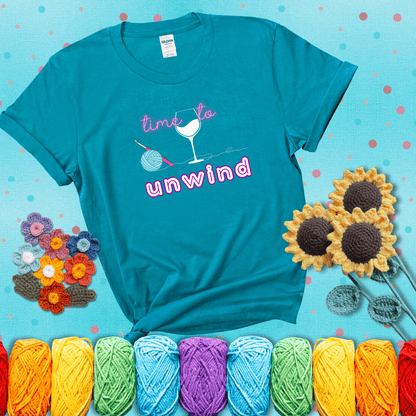 Wine down with your yarn out Design reads 'Time To Unwind' , perfect crochet gift for yarn lovers showing a blue-green tee with a teal sunflower background