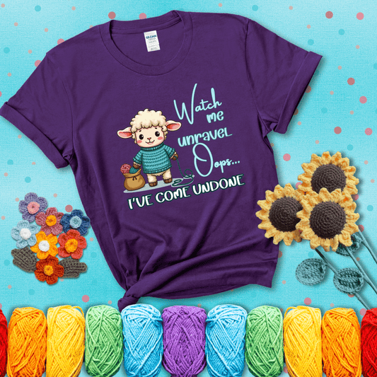 Cute sheep holding yarn looks startled with the phrase “Watch me unravel… Oops, I’ve come undone.” Perfect mix of whimsy and yarn life chaos, showing a purple tee with a teal sunflower background