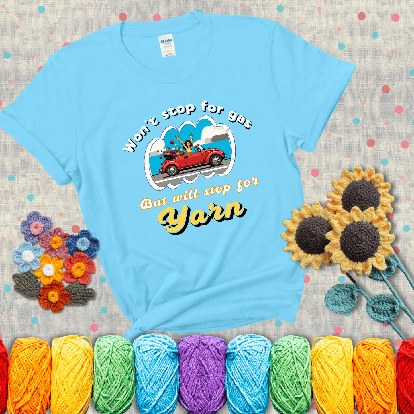 Woman joyfully driving a red convertible overflowing with yarn balls, paired with bold retro lettering and a playful slogan showing a light blue tee with grey sunflower background