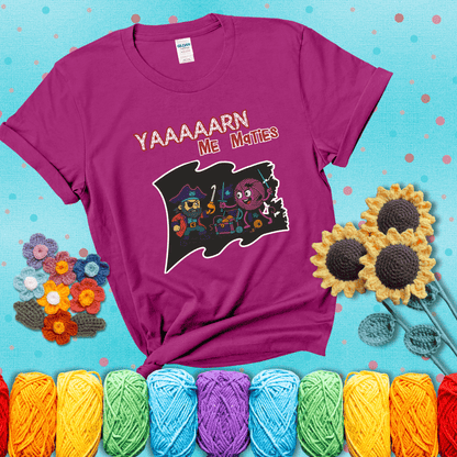 A pirate with a crochet hook for a hand duels a fierce yarn ball wielding knitting needles, standing in front of a treasure chest filled with yarn showing a magenta tee with a teal sunflower background
