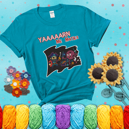A pirate with a crochet hook for a hand duels a fierce yarn ball wielding knitting needles, standing in front of a treasure chest filled with yarn showing a blue-green tee with a teal sunflower background