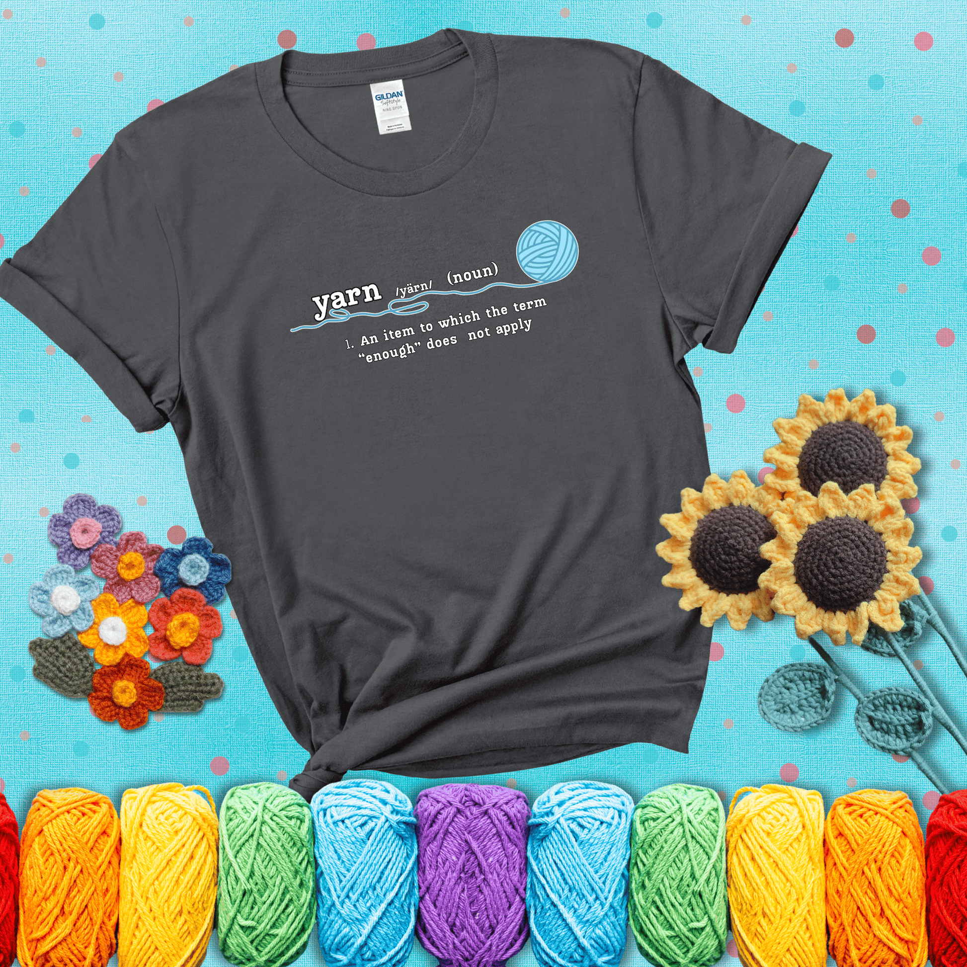 A definition-style graphic showing the word "yarn" as a noun, with the definition “An item to which the term ‘enough’ does not apply,” and a ball of blue yarn with a loose strand showing a dark grey tee with a teal sunflower background