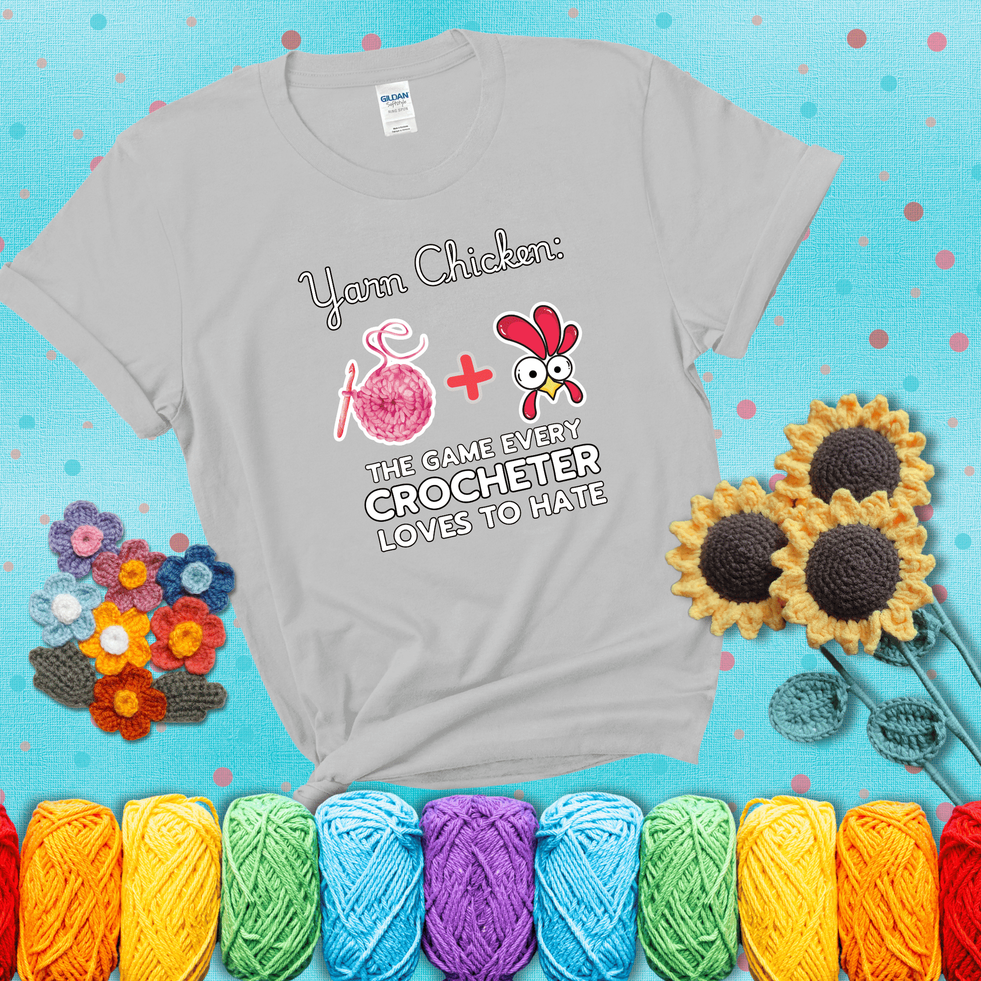 Cartoon chicken inside a yarn ball with crochet circle background. Text reads: “Yarn Chicken: The Game Every Crocheter Loves to Lose.” A fun and relatable tee for fiber artists who like to live on the edge, showing a light grey tee with a teal sunflower background