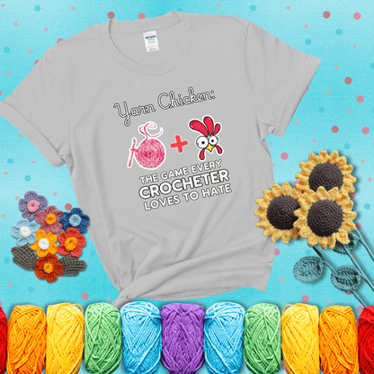 Cartoon chicken inside a yarn ball with crochet circle background. Text reads: “Yarn Chicken: The Game Every Crocheter Loves to Lose.” A fun and relatable tee for fiber artists who like to live on the edge, showing a light grey tee with a teal sunflower background