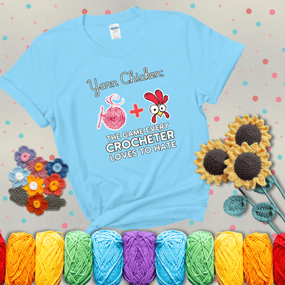Cartoon chicken inside a yarn ball with crochet circle background. Text reads: “Yarn Chicken: The Game Every Crocheter Loves to Lose.” A fun and relatable tee for fiber artists who like to live on the edge, showing a light blue tee with grey sunflower background