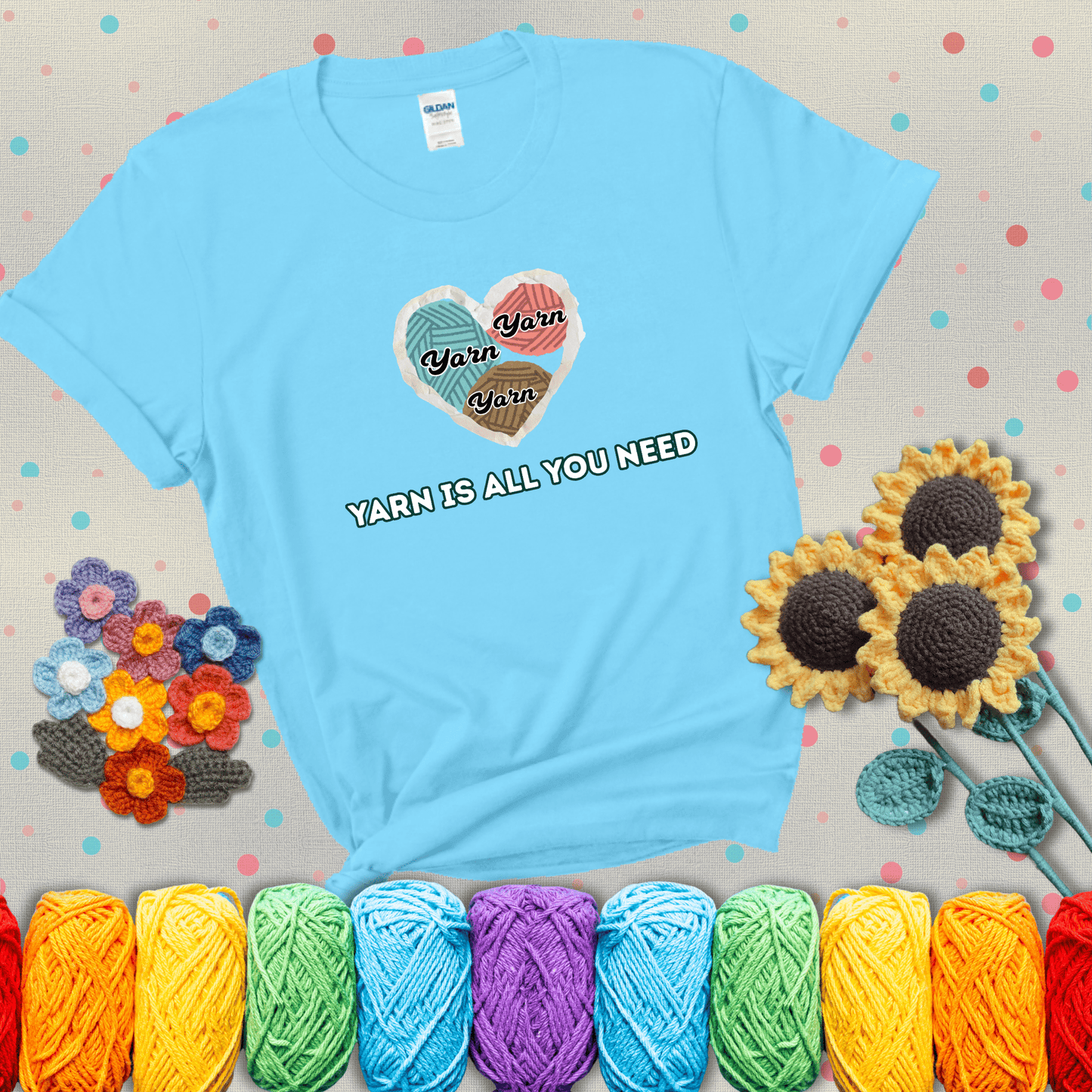 Heart made of yarn textures labeled “Yarn” in different colors above the phrase “Yarn is all you need” in bold retro type, showing a light blue tee with grey sunflower background