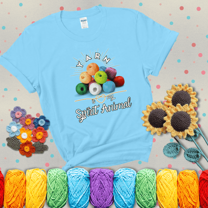 Stack of colorful yarn balls with radiant glow. Text reads: “Yarn Is My Spirit Animal.” A calming and colorful tee for fiber lovers who find zen in stitching, showing a light blue tee with grey sunflower background