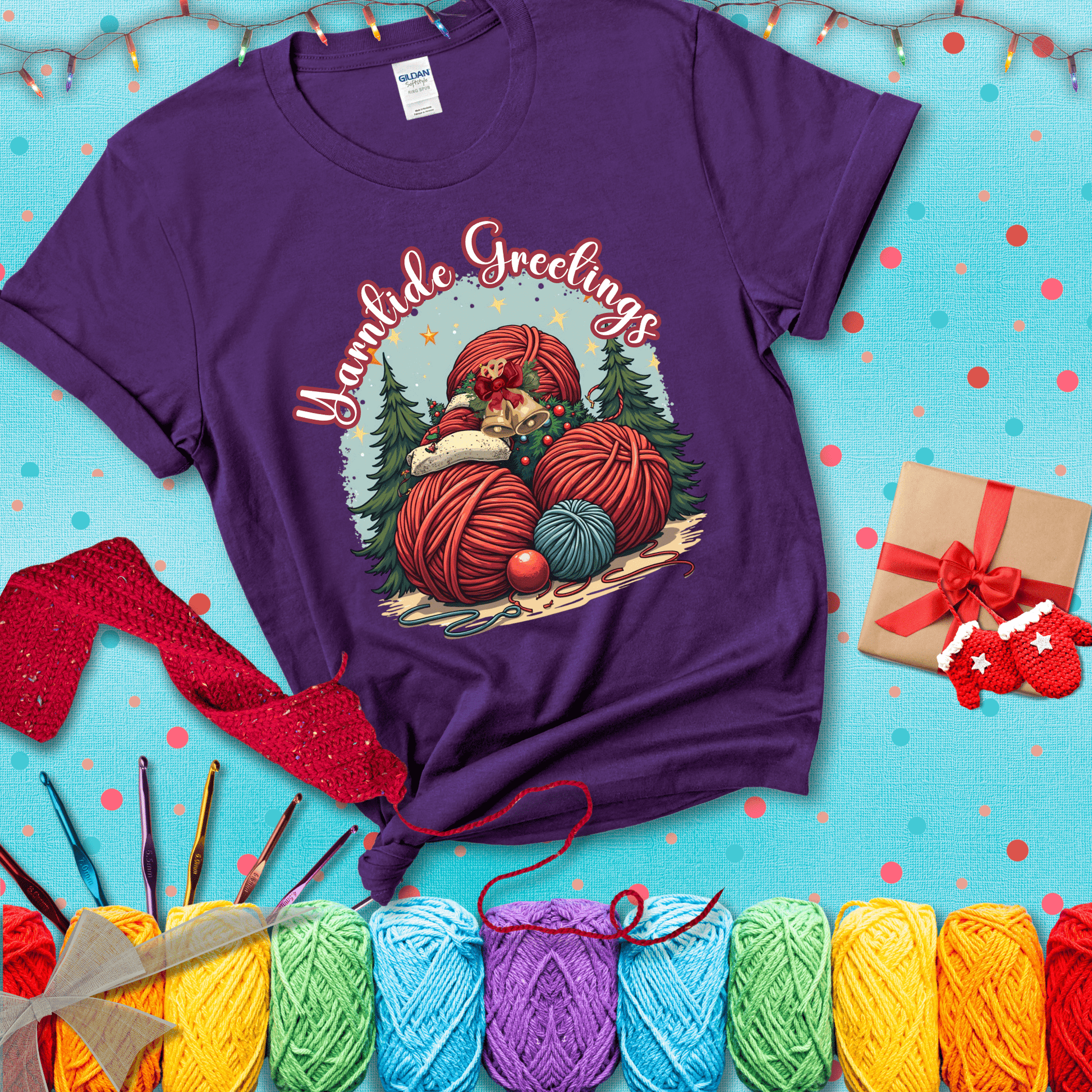 Pile of colorful yarn balls with bells, bows, and trees, with the phrase “Yarntide Greetings.” Cozy and festive holiday crochet tee, showing a purple tee with a festive Christmas background